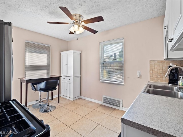 4707 Grantwood Dr, Parma, OH 44134 - kitchen featuring white cabinets, ceiling fan, light tile patterned flooring, decorative backsplash, and a textured ceiling