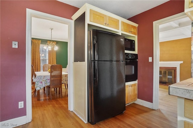 7219 N Lima Rd, Poland, OH 44514 - kitchen featuring black appliances, light wood-style floors, a chandelier, and a fireplace