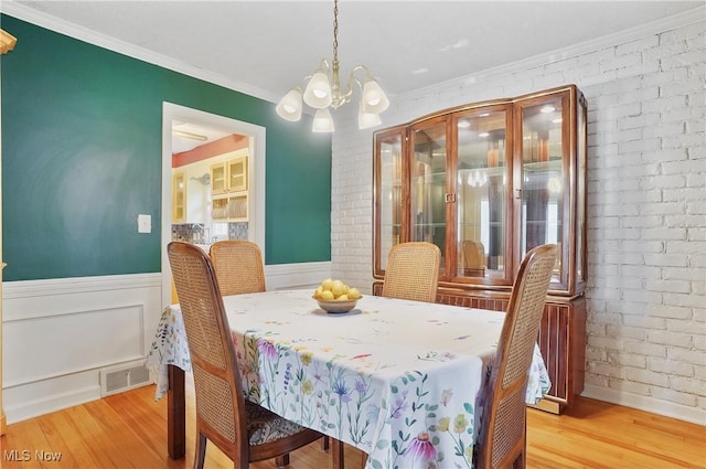7219 N Lima Rd, Poland, OH 44514 - dining area with a chandelier, light wood-style floors, ornamental molding, wainscoting, and brick wall