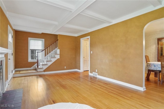 7219 N Lima Rd, Poland, OH 44514 - unfurnished living room featuring light wood-type flooring, beam ceiling, arched walkways, stairs, and coffered ceiling
