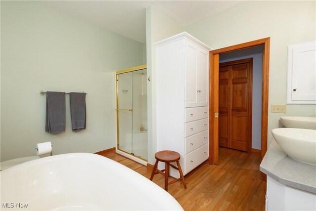 121 Sycamore Pl, Oberlin, OH 44074 - full bath featuring a stall shower, double vanity, a soaking tub, and wood finished floors