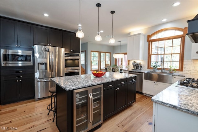 121 Sycamore Pl, Oberlin, OH 44074 - kitchen featuring appliances with stainless steel finishes, wine cooler, dark cabinetry, a kitchen island, and light stone countertops