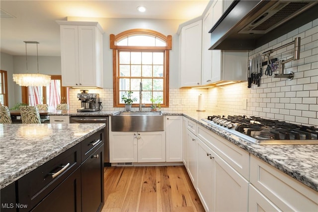 121 Sycamore Pl, Oberlin, OH 44074 - kitchen with stainless steel gas stovetop, extractor fan, white cabinetry, light wood-type flooring, and a chandelier