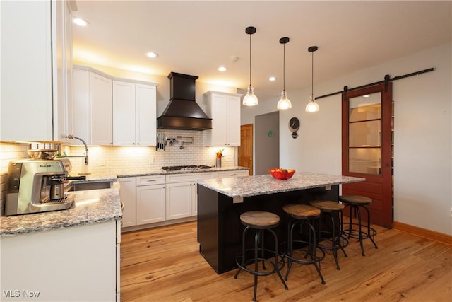121 Sycamore Pl, Oberlin, OH 44074 - kitchen featuring premium range hood, white cabinets, a kitchen island, light wood finished floors, and a barn door