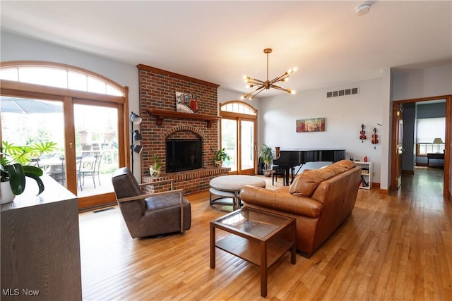 121 Sycamore Pl, Oberlin, OH 44074 - living room featuring light wood-style floors, a chandelier, and a brick fireplace