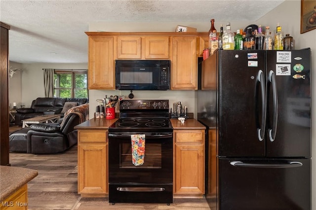 1345 County Road 16, New London, OH 44851 - kitchen featuring black appliances, dark countertops, light wood-type flooring, open floor plan, and a textured ceiling