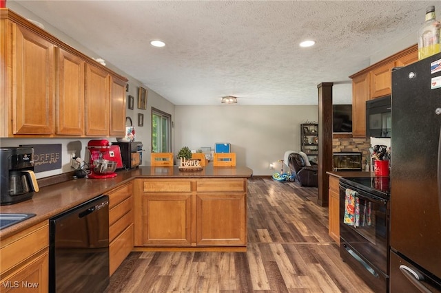 1345 County Road 16, New London, OH 44851 - kitchen featuring black appliances, a textured ceiling, a peninsula, wood finished floors, and brown cabinetry