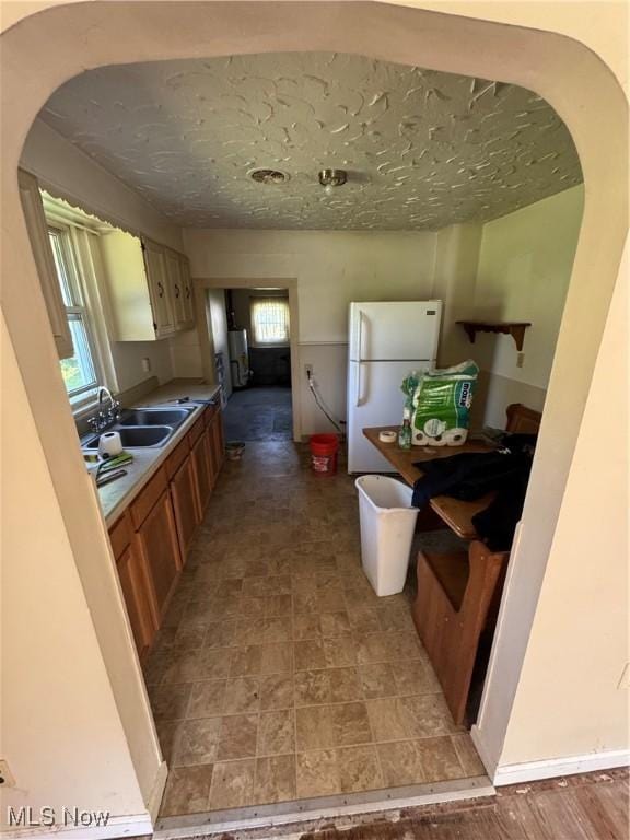 7138 Jefferson Rd, Ashtabula, OH 44004 - kitchen with freestanding refrigerator, arched walkways, and brown cabinets