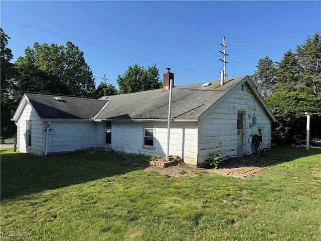 7138 Jefferson Rd, Ashtabula, OH 44004 - back of house featuring a lawn, a chimney, and roof with shingles