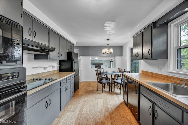 12084 Heath Rd, Chesterland, OH 44026 - kitchen featuring black appliances, a chandelier, under cabinet range hood, light wood-type flooring, and hanging light fixtures