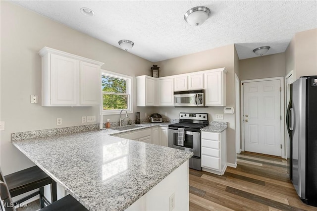 4670 King Meadow Trl, Kent, OH 44240 - kitchen with stainless steel appliances, a peninsula, white cabinetry, a textured ceiling, and a breakfast bar area