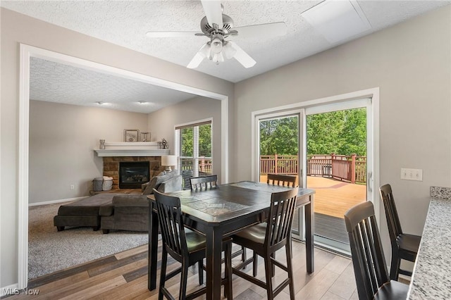 4670 King Meadow Trl, Kent, OH 44240 - dining area with light wood-type flooring, a textured ceiling, a fireplace, and a ceiling fan