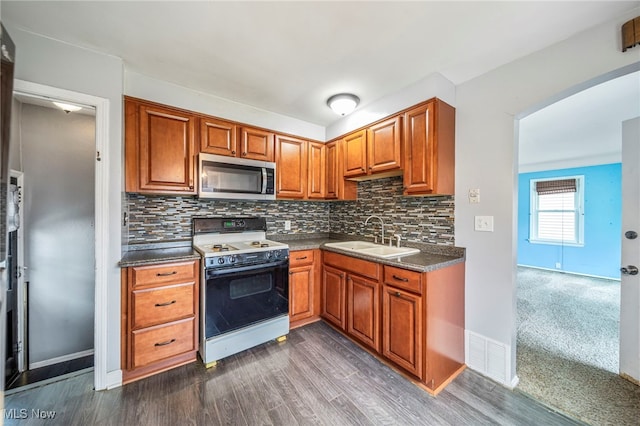 6306 Gilbert Ave, Parma, OH 44129 - kitchen featuring white range with electric stovetop, stainless steel microwave, tasteful backsplash, dark wood finished floors, and brown cabinets