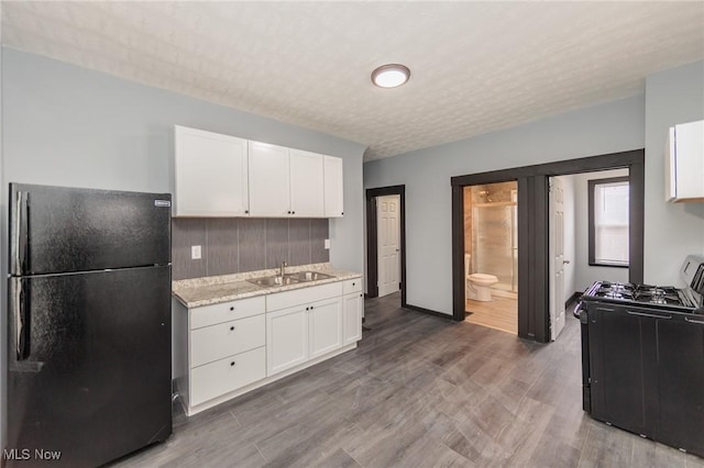 1431 Rowley Ave, Cleveland, OH 44109 - kitchen with black appliances, white cabinetry, wood finished floors, tasteful backsplash, and light stone countertops