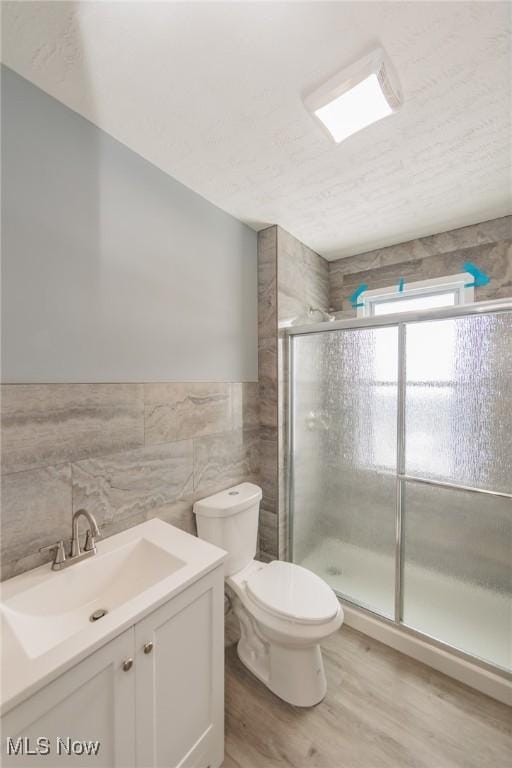 1431 Rowley Ave, Cleveland, OH 44109 - full bathroom featuring wood finished floors, tile walls, a shower stall, vanity, and wainscoting