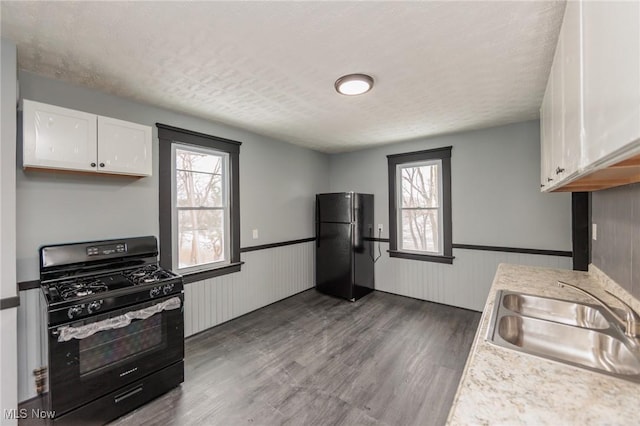1431 Rowley Ave, Cleveland, OH 44109 - kitchen featuring black appliances, wainscoting, white cabinets, wood finished floors, and light countertops