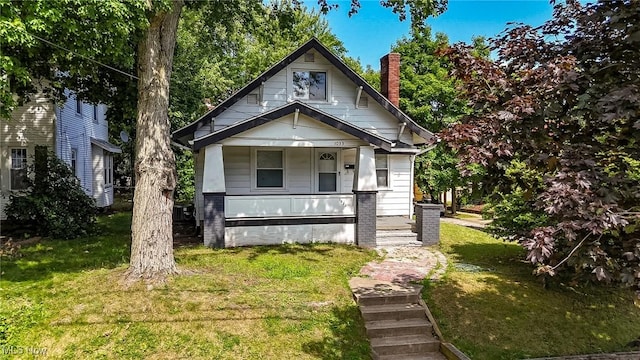 1033 Chalker St, Akron, OH 44310 - view of front of house featuring covered porch, a chimney, and a front lawn
