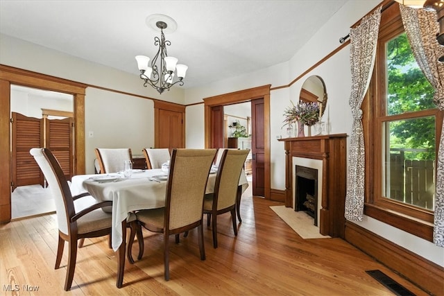 201 E Spring St, Marietta, OH 45750 - dining room with light wood-style flooring, a chandelier, and a fireplace with flush hearth