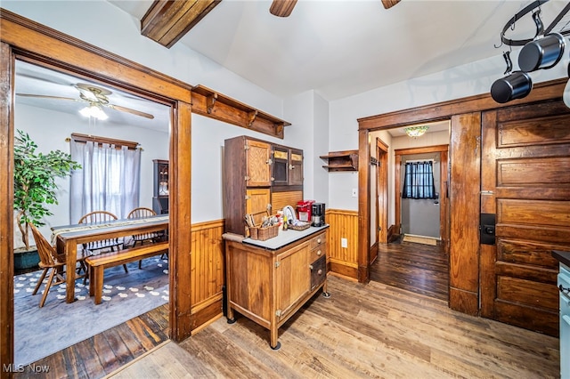 1833 W 7th St, Ashtabula, OH 44004 - kitchen with ceiling fan, light wood finished floors, a wainscoted wall, brown cabinetry, and wooden walls