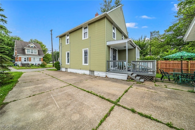 1833 W 7th St, Ashtabula, OH 44004 - back of house with a chimney, a porch, a patio, and driveway
