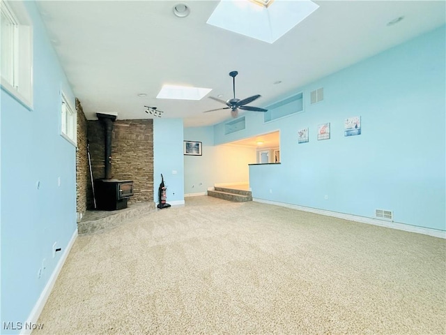 133 Walleye Ct, Lagrange, OH 44050 - unfurnished living room with a skylight, a wood stove, ceiling fan, and carpet