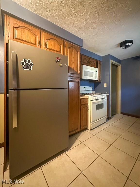 1422 Youll St, Niles, OH 44446 - kitchen featuring white appliances, light tile patterned floors, a textured ceiling, brown cabinetry, and light countertops