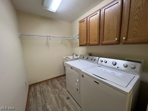 2132 University Commons Dr SE, Massillon, OH 44646 - laundry area featuring cabinet space, separate washer and dryer, wood finished floors, and a textured ceiling
