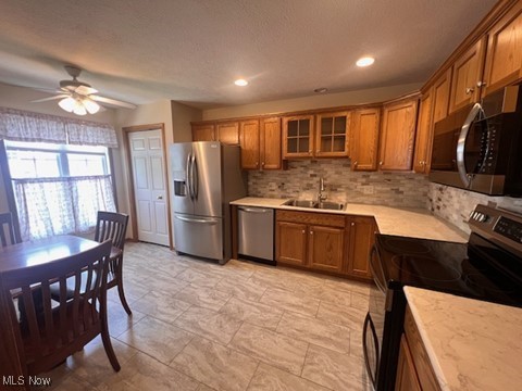2132 University Commons Dr SE, Massillon, OH 44646 - kitchen featuring stainless steel appliances, brown cabinets, light countertops, backsplash, and ceiling fan
