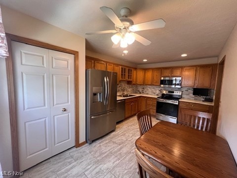 2132 University Commons Dr SE, Massillon, OH 44646 - kitchen with stainless steel appliances, brown cabinets, a ceiling fan, tasteful backsplash, and light countertops
