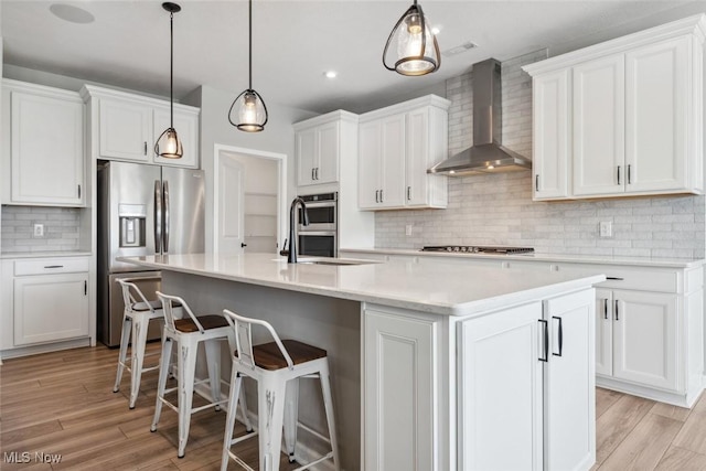 23761 St Andrews Dr, Columbia Station, OH 44028 - kitchen with wall chimney exhaust hood, appliances with stainless steel finishes, decorative backsplash, white cabinetry, and a center island with sink