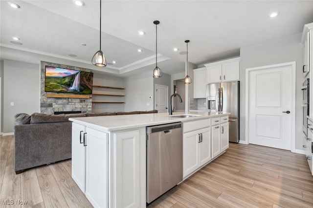 23761 St Andrews Dr, Columbia Station, OH 44028 - kitchen with appliances with stainless steel finishes, light wood-style flooring, a fireplace, an island with sink, and open floor plan