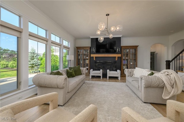 7324 Roman Ave NW, Massillon, OH 44646 - living area featuring arched walkways, light wood finished floors, a chandelier, stairway, and a large fireplace
