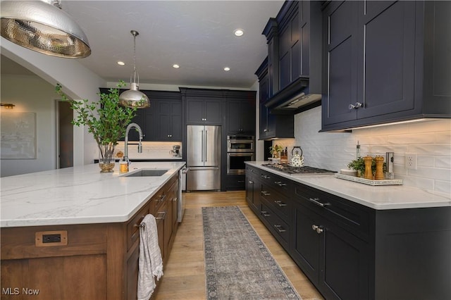 7324 Roman Ave NW, Massillon, OH 44646 - kitchen featuring appliances with stainless steel finishes, light wood-style flooring, backsplash, light stone countertops, and a large island with sink