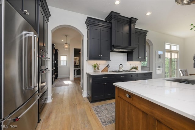 7324 Roman Ave NW, Massillon, OH 44646 - kitchen featuring stainless steel appliances, arched walkways, light wood-type flooring, tasteful backsplash, and recessed lighting