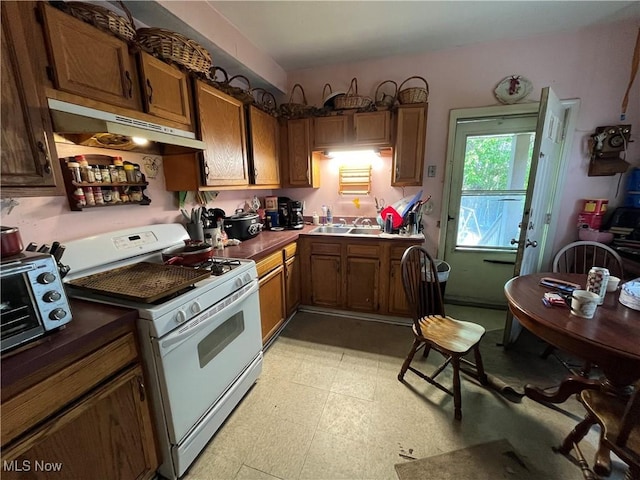 2455 W 7th St, Cleveland, OH 44113 - kitchen featuring gas range gas stove, under cabinet range hood, light floors, and brown cabinets