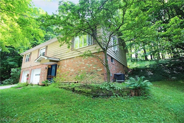8630 Williams Rd, Chardon, OH 44024 - view of side of home with brick siding, an attached garage, a yard, and driveway