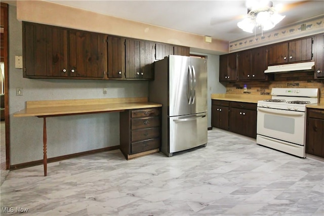 8630 Williams Rd, Chardon, OH 44024 - kitchen with white gas range oven, freestanding refrigerator, built in study area, under cabinet range hood, and dark brown cabinets