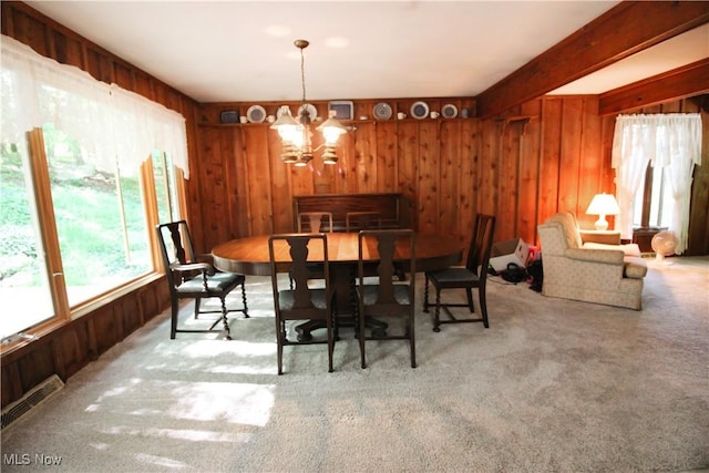 8630 Williams Rd, Chardon, OH 44024 - carpeted dining space featuring wooden walls, a chandelier, and beam ceiling