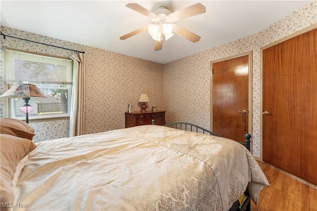 218 Bonnett St SW, North Canton, OH 44720 - bedroom featuring wood finished floors, a ceiling fan, wallpapered walls, and two closets