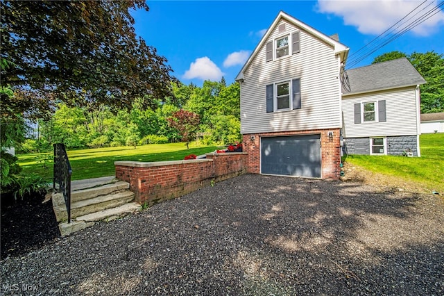 416 N Hambden St, Chardon, OH 44024 - view of side of home with driveway, a lawn, an attached garage, brick siding, and view of wooded area