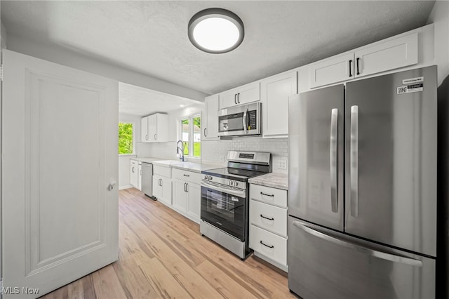 416 N Hambden St, Chardon, OH 44024 - kitchen with stainless steel appliances, light countertops, light wood-style flooring, white cabinets, and decorative backsplash