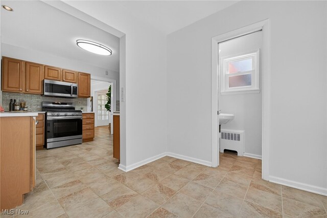 3294 Avalon Rd, Shaker Heights, OH 44120 - kitchen with stainless steel appliances, radiator heating unit, light countertops, tasteful backsplash, and brown cabinetry