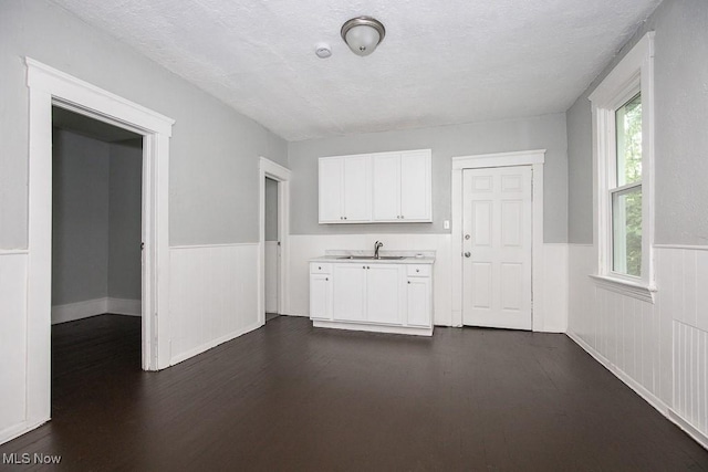 8023 Kosciuszko Ave, Cleveland, OH 44103 - kitchen featuring a wainscoted wall, dark wood-style flooring, white cabinets, light countertops, and a textured ceiling