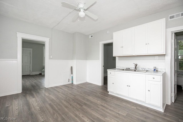 8023 Kosciuszko Ave, Cleveland, OH 44103 - kitchen with ceiling fan, dark wood-style flooring, light countertops, white cabinetry, and a wainscoted wall
