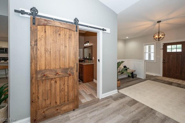 2692 Aspen Dr, Girard, OH 44420 - entryway with a barn door, wood finished floors, a chandelier, and vaulted ceiling