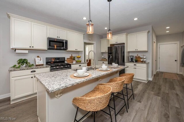 2692 Aspen Dr, Girard, OH 44420 - kitchen featuring appliances with stainless steel finishes, dark wood-type flooring, a kitchen bar, white cabinetry, and a center island with sink