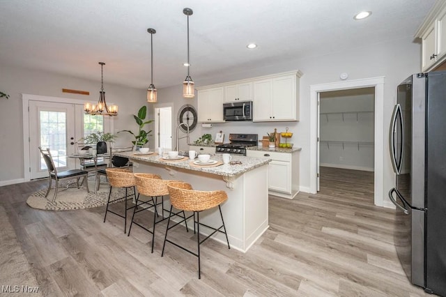 2692 Aspen Dr, Girard, OH 44420 - kitchen with appliances with stainless steel finishes, light wood-style flooring, light stone counters, a breakfast bar area, and white cabinets