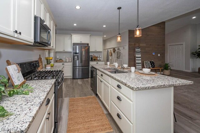 2692 Aspen Dr, Girard, OH 44420 - kitchen with stainless steel appliances, dark wood-type flooring, white cabinets, a center island with sink, and light stone counters
