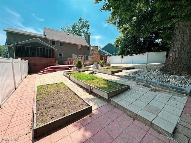 5123 Glenbrook Dr, Vienna, WV 26105 - rear view of house with a vegetable garden, a sunroom, a patio area, and a fenced backyard