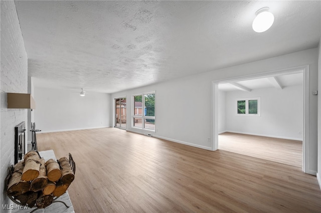 3612 Vezber Dr, Seven Hills, OH 44131 - unfurnished living room with wood finished floors, a textured ceiling, a large fireplace, and healthy amount of natural light